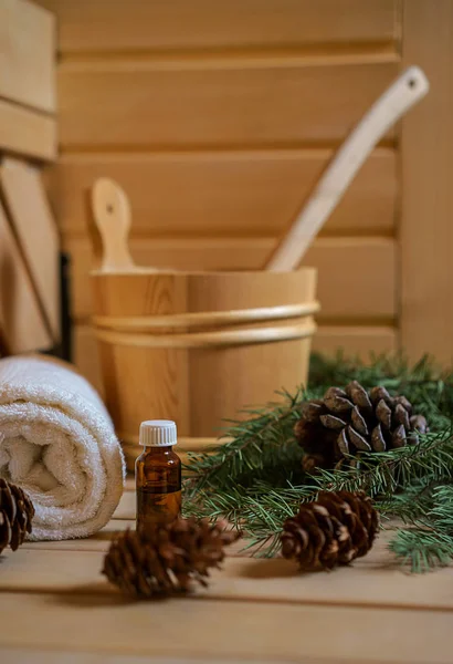 Spa, sauna ve sağlık ayarı su kovası ile yağ özü, koniler, Noel ağaç dalları, ahşap arka plan üzerinde beyaz havlu. Sonbahar Kış sağlık kavramı relax ve tedavi tedavi. Yakın çekim