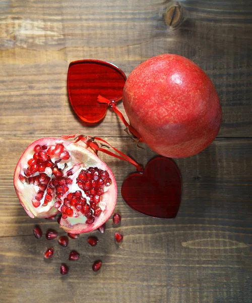 Pomegranates with ruby red beans in love with two hearts on wooden table background, selective focus, rustic style. Valentines day Valentine concept of healthy diet lifestyle — Stock Photo, Image
