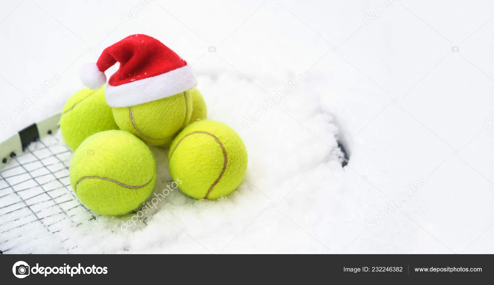 Santa hat on tennis ball, set of tennis balls on racket on white snow winter  background. Merry Christmas and New year concept with tennis balls play.  Close up, sport lifestyle, funny. Stock