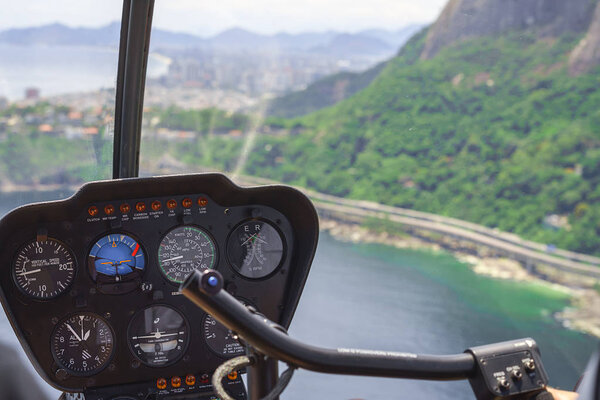 View from a helicopter cockpit flying over Rio de Janeiro. Cockpit with instruments panel. Captain in the aircraft cockpit.
