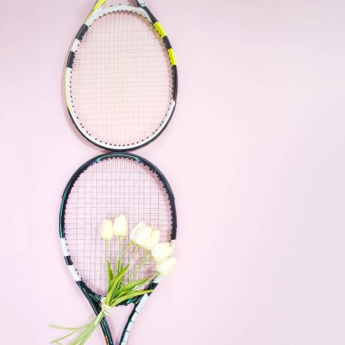 Uluslararası Kadınlar Günü 8 Mart şekli tenis raketleri buket beyaz laleler ve pastel pembe bir arka plan üzerinde kopya alanı ile yapılır. Tenis oyun ile Sevgililer günü kavramı. Düz yatıyordu