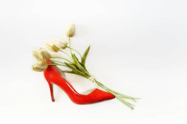 Chaussures à talons hauts rouges pour dames remplies de tulipes blanches bouquet et copiez de l'espace sur fond blanc. Valentines jour mère femme mise en page. Pose plate, horizontale — Photo