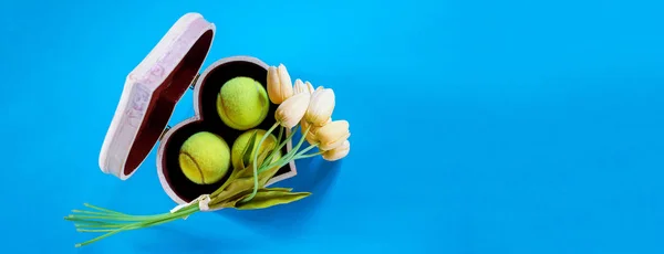 Tenis aşk düzen tenis topları ile mavi zemin üzerine beyaz lale buketi kalp şeklinde kutusunda. Bayan günü Mart 8. Uzay kopyalayın. Tenis oyun ile Sevgililer günü kavramı. Düz yatıyordu