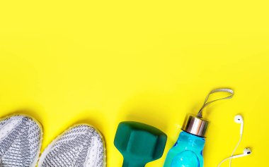 Fitness ekipmanları ve sarı renk arka plan üzerinde metin için yer düz yatıyordu kompozisyonu. sağlıklı ve aktif yaşam kavramı spor spor ayakkabı, şişe suları kulaklık dumbbells seviyorum.
