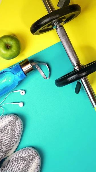 Fitness ekipmanları ve sarı mavi renk arka plan üzerinde metin için yer ile üstten görünüm düzeni. sağlıklı ve aktif yaşam tarzları seviyorum konsept spor spor ayakkabı, halter, şişe suları, elma, kulaklık.