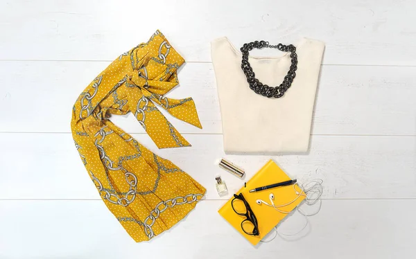 Top view fashion female outfit layout with trendy chain print: yellow skirt sweater jewelry glasses makeup on white wooden background. День Святого Валентина концепции офиса. Элегантность . — стоковое фото