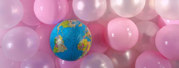 Creative layout for World Environment Day - Plastic Free. The globe as symbol of the Earth on the top of bunch of pink plastic balls. Concept of saving the environment, pollution. Copy space, flat lay