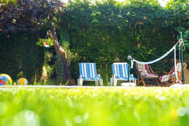 Arkadaşlar garden parti için yeşil çim su damlaları ve Yüzme Havuzu ve şezlonglar avluda yeşil bokeh arka plan ile. Seçici odak. Kavram yaz dinlenme ve tatil için