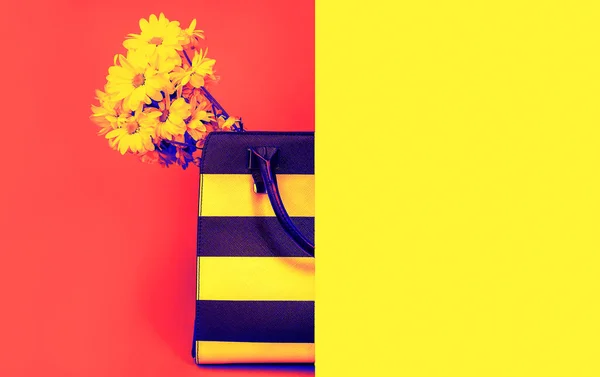 Concepto moderno bolso de accesorios femeninos y flores amarillas sobre vivo color rojo neón y fondo amarillo. Traje de moda elegante. Concepto de estilo de vida mínimo. Efecto Duotone. Copiar espacio — Foto de Stock