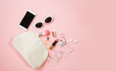 Düz kadın aksesuarlar kozmetik güneş gözlüğü cep telefonu kulaklık flash sürücü makyaj pastel pembe arka plan üzerinde yatıyordu. Sevgililer günü 8 Mart doğum günü yaz parti kıyafet düzeni. Üstten Görünüm