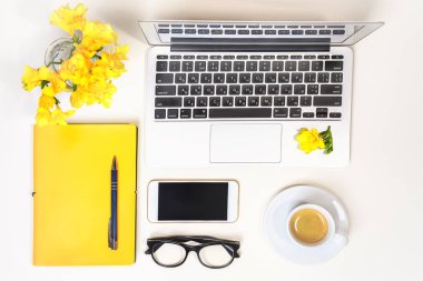 Bayan ev ofis büro. Çalışma alanı ile laptop, bilgisayar, sarı defter, moda gözlük, fincan kahve, cep telefonu ve beyaz arka plan üzerinde çiçek. Düz yatıyordu. Üstten Görünüm. Kavram online alışveriş.