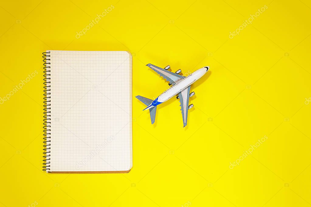 Minimal layout with model airplane, spiral notebook on yellow background. Directly above. Travel, vacation, summer concept. flat lay, top view composition.
