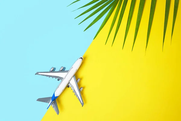 Modelo avião plano ou plano e folhas de palma verde tropical sobre fundo amarelo e azul . — Fotografia de Stock