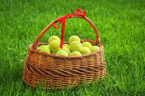 Piłki tenisowe w koszyku na zielonej trawie. — Zdjęcie stockowe
