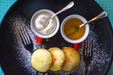 Sağlıklı kahvaltı yazlık cheesecakes Rus sirniki bal ve mavi arka plan üzerinde kahvaltı için ekşi krema ile.