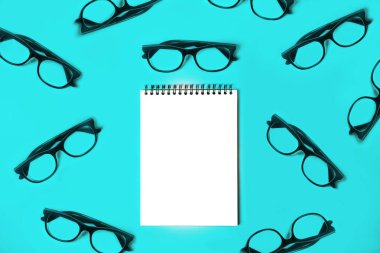 Mavi arka plan üzerinde trendy gözlüklü not defteri.