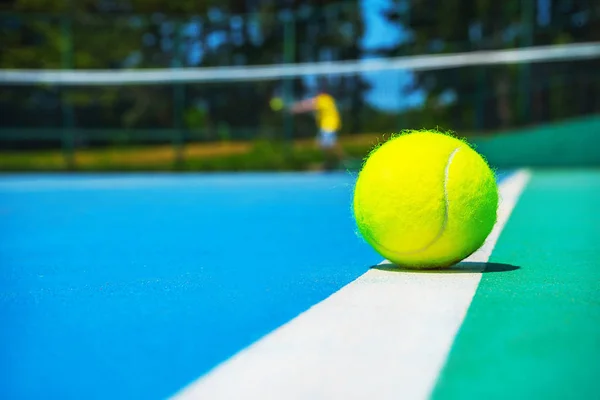 Tennis boll på White Court line på Hard modern Blue Green Court med spelare, netto, bollar, träd på bakgrunden. — Stockfoto