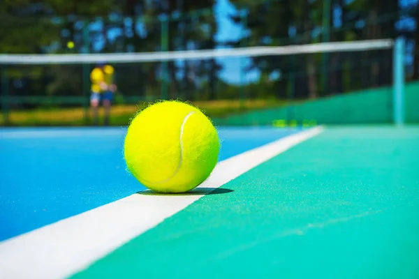 Tennis boll på White Court line på Hard modern Blue Green Court med spelare, netto, bollar, träd på bakgrunden. — Stockfoto
