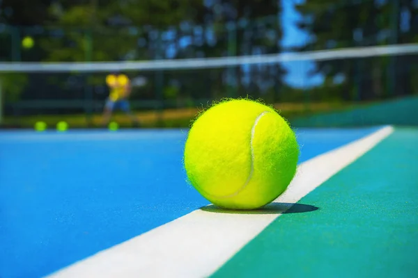 Tennis boll på White Court line på Hard modern Blue Green Court med spelare, netto, bollar, träd på bakgrunden. — Stockfoto