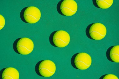 Yeşil arka plan üzerinde tenis topu ile yapılan yaratıcı kompozisyon.