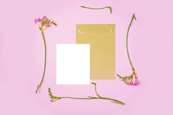 Lapos feküdt shot fehér betűs lapot és az öko papír borítékot a rózsaszín háttér. Meghívók vagy szerelmes levél rózsaszín Liliomos virággal. — Stock Fotó