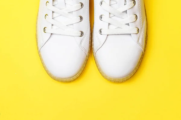 White sneakers are lying on a pastel yellow background. — Stock Photo, Image