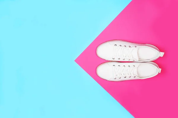 White sneakers are lying on bright neon color blue pink background. — Stock Photo, Image