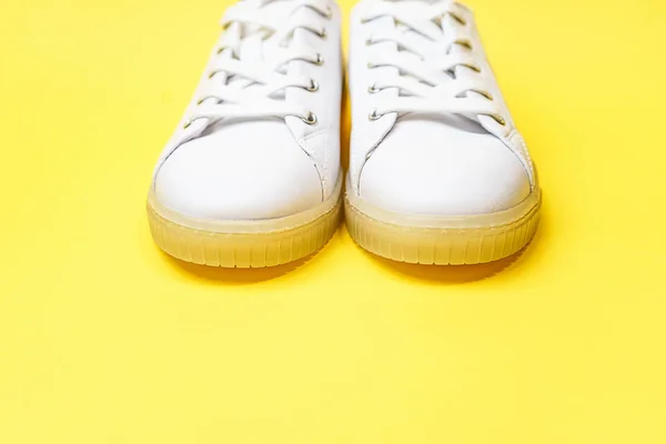 White sneakers are lying on a bright yellow background. — Stock Photo, Image