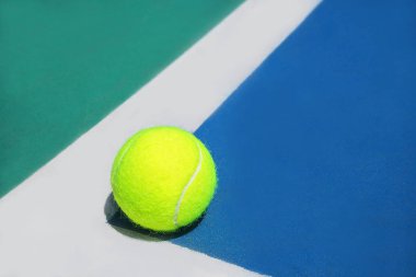 Sert tenis kortu köşesinde beyaz çizgi üzerinde tenis topu ile yaz spor konsepti.