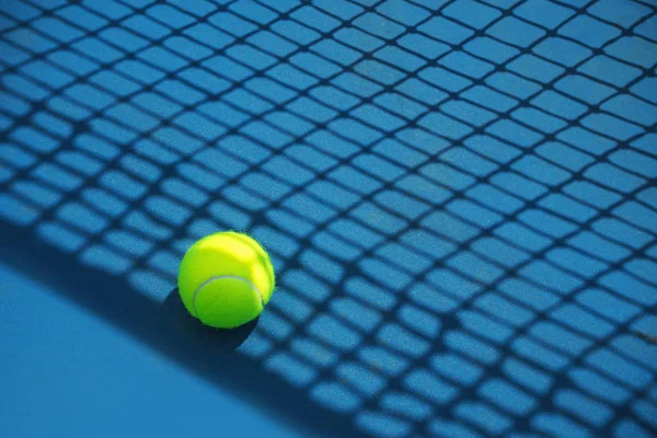 Summer sport concept with tennis ball and net on hard tennis court.