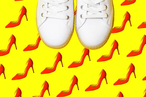 Fashion white sneakers against female red shoes pattern on bright yellow background. — Stock Photo, Image