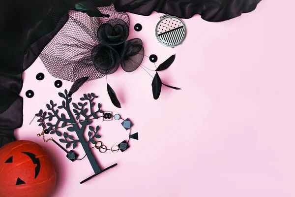Halloweenské party Doplňky k samičí výbavu černý na světle růžovém pozadí: dýně, šperky, klobouk s rouškou a pérem, doplní. — Stock fotografie