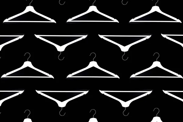 Fashion clothes hanger pattern on black background.