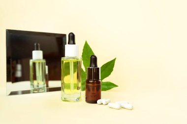 Bitkisel CBD yağlı cam şişeler, THC tentürü, haplar, ayna ve kenevir yaprağı..