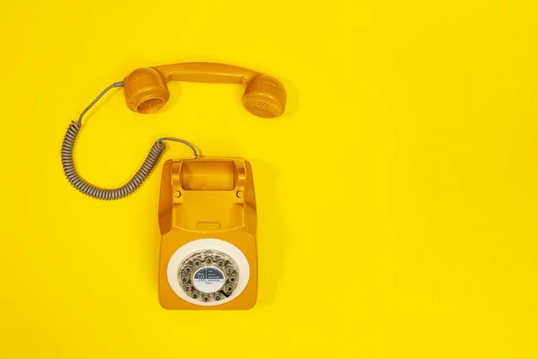 Auricular amarillo de un teléfono sobre un fondo amarillo . — Foto de Stock