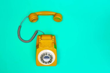 Yeşil nane arkaplanındaki sarı telefon ahizesi. 