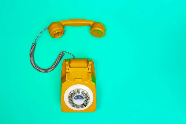 Auricular amarillo de un teléfono sobre un fondo verde menta. — Foto de Stock