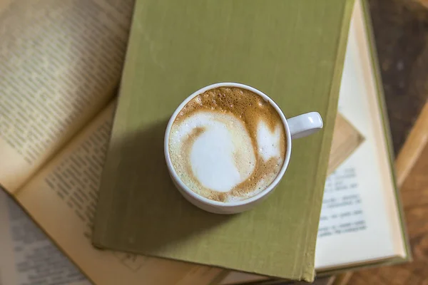 cup of latte or cappuccino coffee with a book in coffee shop
