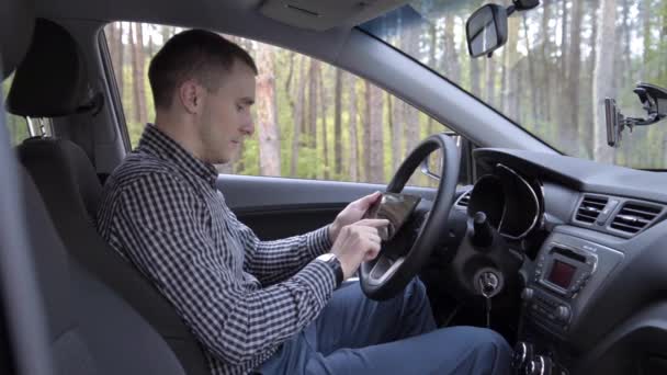 Homme assis en voiture avec tablette numérique — Video