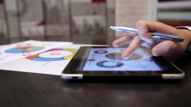 Bir ofiste otururken istatistikleri ile çalışma iş adamı. Tablet kullanan adam