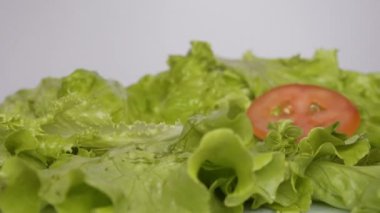 Yeşil salatanın üzerine düşen domates dilimlerinin yakın çekim ilerki masaya yayıldı