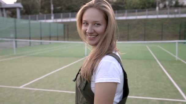 Χαμογελαστή Κοπέλα Που Κοιτάζει Την Κάμερα Στο Γήπεδο Του Τένις — Αρχείο Βίντεο