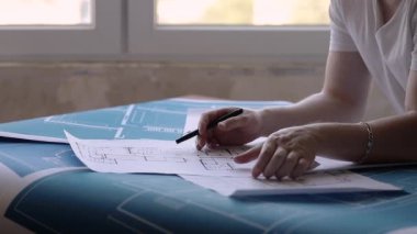 Mimar masanın üzerine bina planlarını kontrol eder
