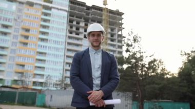 İnşaat mühendisi kameraya bakıyor.
