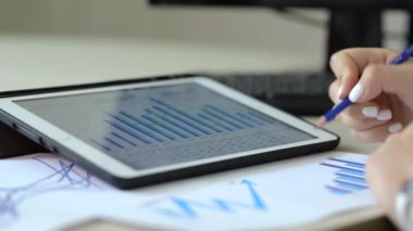 İş kadını ofiste mali grafikler ve çizelgeler üzerinde çalışıyor.