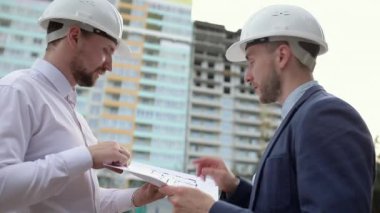 İki inşaat mühendisi bir inşaat planını tartışıyor.