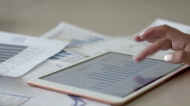 Muhasebeci kız ofis masasında mali belgelere bakıyor. İş kadını tabletten çizelgeleri izliyor