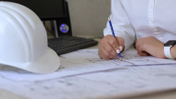 Construction engineer makes notes on the drawings sitting in the office