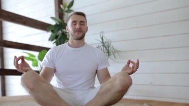 Kamera, evinde yoga yapan bir gencin etrafında dönüyor.