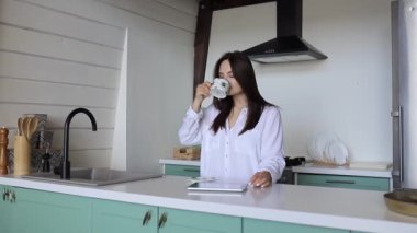 Kız sabahları mutfakta kahve içer.